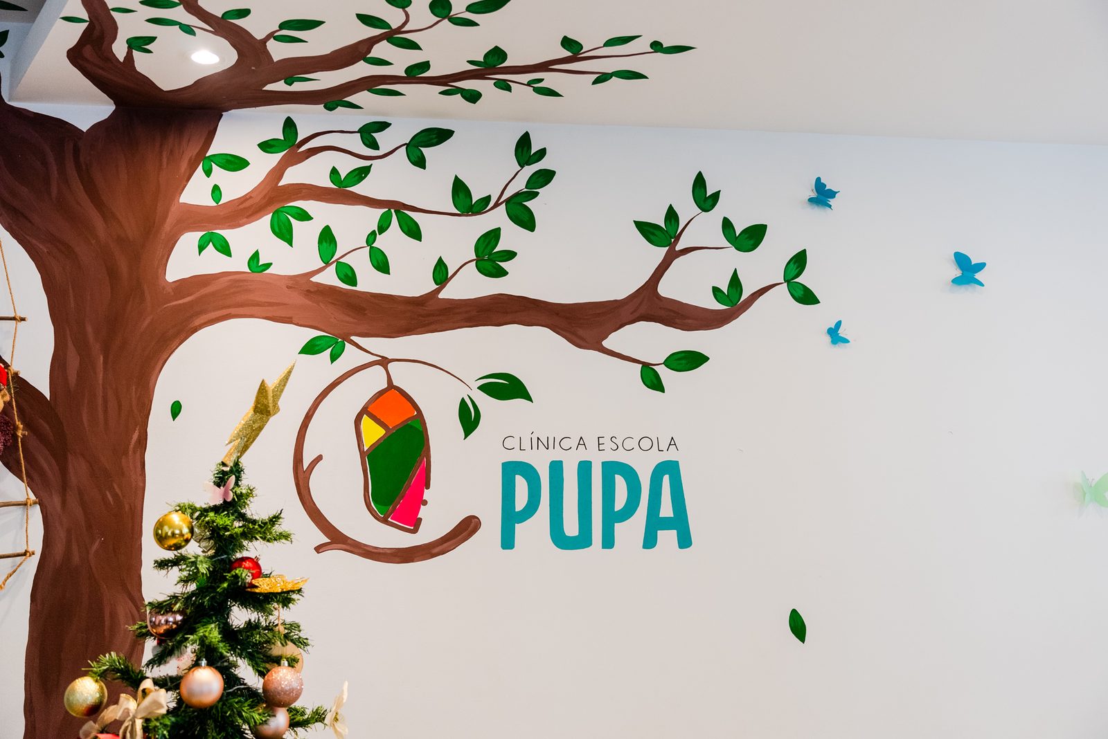 Mural com árvore e logo PUPA no interior da clínica